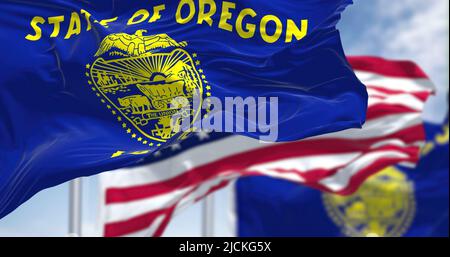 Die Staatsflagge von Oregon winkt zusammen mit der Nationalflagge der Vereinigten Staaten von Amerika. Im Hintergrund ist der Himmel klar. Oregon ist eine US-amerikanische St. Stockfoto