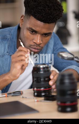 Mann, der studiert, wie man die Kamera repariert Stockfoto