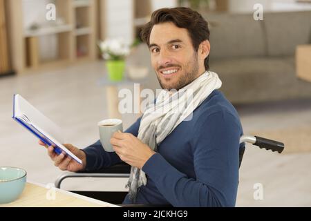 Ein hübscher behinderter Mann im Rollstuhl, der einen Kaffee getrunken hat Stockfoto