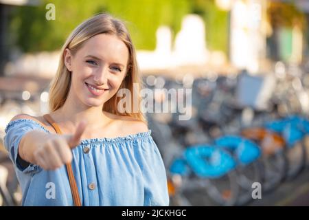 Junge Frau gibt den Daumen nach oben im Freien Stockfoto