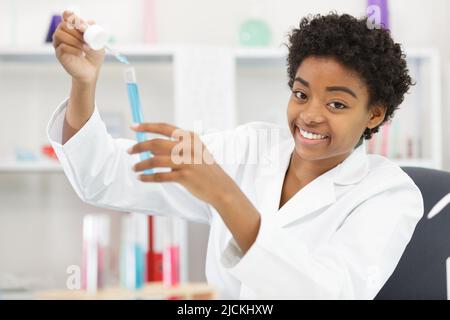 Glücklicher Wissenschaftler, der die Flasche mit Chemikalien beobachtet Stockfoto