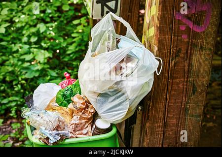 Berlin, Deutschland - 10. Juni 2022: Überfüllter Mülleimer und Abfall in einem öffentlichen Park in Berlin. Stockfoto