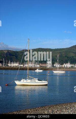 Blick auf Yachten und Motorboote im River Conwy von Deganwy in Nordwales aus gesehen an einem sonnigen Junimorgen mit Conwy Marina auf der anderen Flussseite. Stockfoto