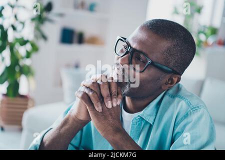 Foto eines verträumten, gut aussehenden, reifen Mannes, der sich am Wochenende beim Brainstorming entspannt und sich wundert, eine Brille zu tragen Stockfoto