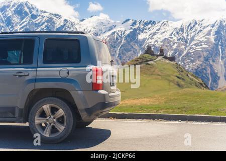 Auto auf dem Weg zur Kirche Gergeti Trinity Tsminda Sameba, Kazbegi, Georgien. Hochwertige Fotos Stockfoto