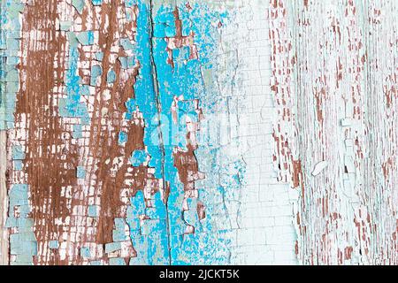 Strukturierte Oberfläche eines alten bemalten Holzbretts mit einer abblätternden und rissigen Schicht aus hellblauer, weißer und roter Farbe in Nahaufnahme. Der gealterte natürliche Holzrücken Stockfoto