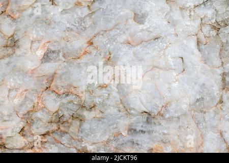 Helle raue Oberfläche aus Marmor mit roten Flecken. Nahaufnahme von rohem Stein, natürlichem Material, schöner Gesteinsstruktur. Abstrakter Hintergrund. Stockfoto