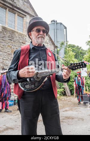 Flagcrackers' Musiker unterstützt die Craven Border Morris-Seite in farbenfrohen Stoffjacken und tanzt beim Open Farm Day in Kappelside in Rathmell. Stockfoto