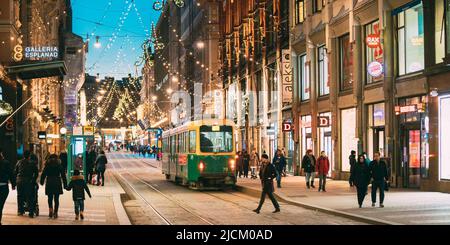 Helsinki, Finnland. Die Straßenbahn fährt von der Haltestelle Aleksanterinkatu Straße. Nacht Abend Weihnachten neues Jahr festliche Beleuchtung auf der Straße. Schöne Stockfoto