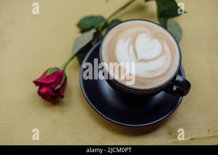 Eine Tasse o Cappuccino mit Latte Art und einer roten Rose. Stockfoto