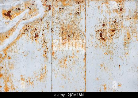 Die Textur eines Metallblechs, bedeckt mit alter grauer, abblätternder Farbe mit Rostflecken und Kratzern. Stockfoto