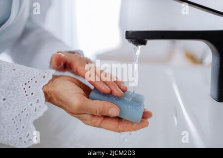 Nahaufnahme einer Frau, die sich mit natürlicher Lavendelseife die Hände wascht, ökologisch nachhaltiger Lebensstil. Stockfoto