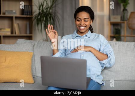 Schwanger Schwarz Frau Machen Video-Anruf Winken Zu Laptop Drinnen Stockfoto