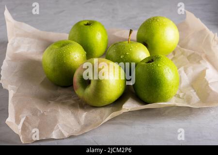 Mehrere frische reife grüne Äpfel liegen auf Pergamentpapier. Stockfoto