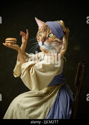 Anmutige weibliche Modell wie mittelalterliche Person in Vintage-Kleidung von Katzenkopf auf dunklen Retro-Hintergrund isoliert geführt. Vergleich von Epochen, Kunstwerk Stockfoto