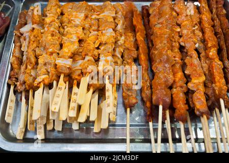 Zubereitete Gerichte zum Verkauf an einem Lebensmittelstand, an dem Fleischgerichte zum Mitnehmen auf Holzspießen verkauft werden, ähnlich wie bei einem chinesischen Sheesh-Kebab. XI'an. China VRC. (125). Stockfoto