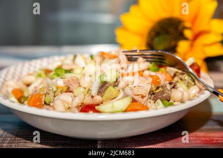 Blick auf den weißen Teller mit gemischtem Salat mit weißen Bohnen und Thunfisch Stockfoto