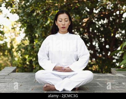 Eine junge Frau praktiziert am frühen Morgen Meditation. Stockfoto