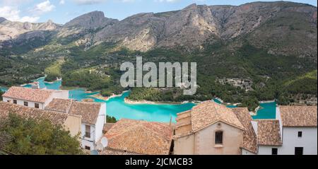 Panoramablick auf die Dächer der Häuser des Dorfes Guadalest mit der Serrella-Bergkette im Hintergrund und dem Guadalest-Stausee Stockfoto