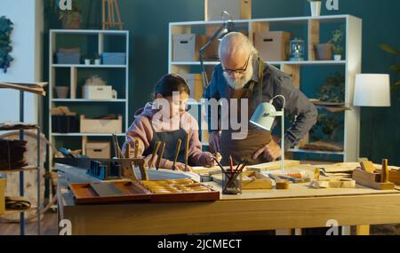 Der fürsorgliche Großvater mit seiner Enkelin im Teenage-Alter verbringt Zeit miteinander, arbeitet am Holz, genießt die Kommunikation im Workshop. Hobby Garage. Kommunikation Stockfoto