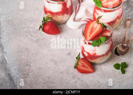 Erdbeerkäsekuchen. Käsekuchen oder Kleinigkeit mit Erdbeere im Glas auf altem grauen Beton Hintergrund Tischhintergrund. Käsekuchen ohne Backen. Abs Stockfoto