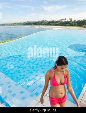 Eine junge Frau verlässt den Hauptpool mit Meerblick in Saman Villas, Aturuwella, Bentota, Sri Lanka. Stockfoto