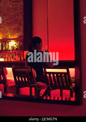 Eine junge asiatische Frau schlisst einen martini an einer Bar. Vientiane, Laos P.D.R. Stockfoto