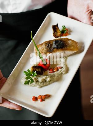 Geröstetes Seebarschfilet mit weicher olivfarbener Tapenade, Aubergine-Kaviar und Baby-Artischocken-Barigoule. Siem Reap, Kambodscha. Stockfoto