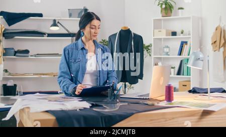 Ein professioneller Modedesigner erstellt in einem Fashion Business Startup Studio eine neue Kollektion, zeichnet, arbeitet mit Skizzen mit einem Laptop. Konzept von H Stockfoto