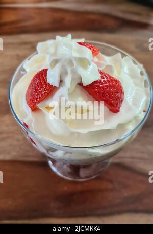 Hausgemachtes Erdbeer-Eis aus frischen Beeren mit Basilikum in Glasschale auf grauem Hintergrund. Weicher Fokus. Stockfoto