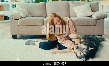 Happy Red haired Teenage Girl Hugs, streichelt ihren Hund, spielt, schaut auf das Tier Stockfoto