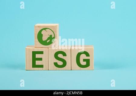 Das Konzept von „Environmental“, „Social“ und „Governance“. Die Wörter auf einem Holzwürfel. Holzwürfel mit der Abkürzung „esgn“ auf blauem Hintergrund Stockfoto