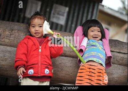 Mountain Province, Philippinen: Zwei Einheimische, junge Mädchen in farbenfroher Kleidung, die sich mit Touristen unterhalten, die in ihrem Viertel in Sagada vorbeikommen. Stockfoto