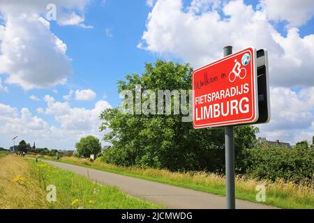 Uikhoven, Belgien - Juin 9. 2022: Rotes Schild mit Nachricht willkommen im Fahrradparadies limburg am Radweg in der ländlichen Landschaft des Flusses Maas Tal Stockfoto