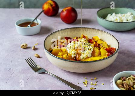 Gesunder Obstsalat mit Nektarine, Ricotta-Creme mit Pistazien und Honig Stockfoto