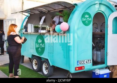 TA-Qali, Malta - 20 2022. Mai: Eine Frau mit Maske bestellt Lebensmittel an einer mobilen Snackbar Stockfoto