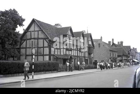 1950s, historische Menschen auf dem Bürgersteig vor einem alten Fachwerkhaus, dem Geburtsort des berühmten englischen Dramatikers William Shakespeare im Jahr 1564, Henley Street, Stratford-upon-Avon, England, Großbritannien. Das elisabethanische Haus, das vermutlich der Geburtsort Shakespeares war und seine frühe Kindheit verbrachte, befand sich in einem großen Verfall, bevor es 1847 von einem gemeinnützigen Verein gebracht und schließlich restauriert wurde. Ein Schild auf dem Bürgersteig sagt: Kein Warten. Diese Seite Heute. Stockfoto