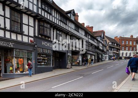 Einkäufer in einer englischen High Street, die von Tudor-Architektur gesäumt ist. Stockfoto