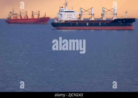 Rostock, Deutschland. 14.. Juni 2022. Die Frachtschiffe 'Dema' (vorne) und 'Dvadesetprvi Maj' liegen auf den Straßen vor dem Hafen von Rostock. Am Horizont ziehen Regenwolken vor der tiefen Abendsonne über die Ostsee. Quelle: Jens Büttner/dpa/Alamy Live News Stockfoto