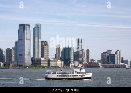 Miss Ellis Island of Statue City Cruises mit Jersey City Hochhaus im Hintergrund in New Jersey, USA Stockfoto