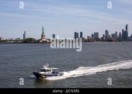 Polizeiboot der NYPD Harbour Unit mit Freiheitsstatue im Hintergrund in New York City, Vereinigte Staaten von Amerika Stockfoto