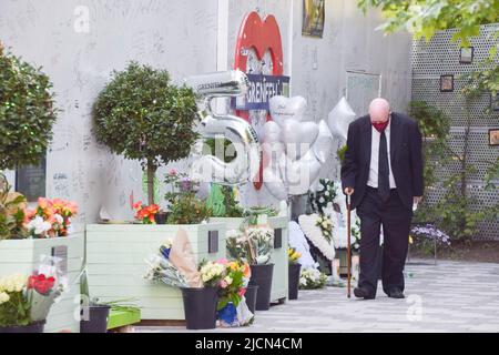 London, England, Großbritannien. 14.. Juni 2022. Ein älterer Mann geht an den Ehrungen und Botschaften an einer Wand neben dem Grenfell Tower Vorbei Zum fünften Jahrestag der Katastrophe im Grenfell Tower fand ein Gedenkgottesdienst statt. 72 Menschen starben, als im Jahr 2017 ein Feuer auf dem Wohnblock in West London ausbrach. (Bild: © Vuk Valcic/ZUMA Press Wire) Stockfoto