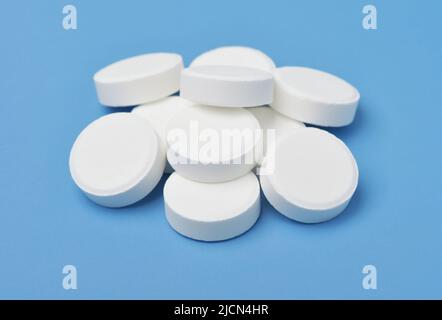 Gruppe von weißen medizinischen Pillen auf blauem Hintergrund isoliert Stockfoto