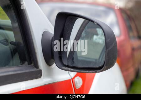 Rechter Rückspiegel aus schwarzem Kunststoff an einem weißen Auto. Außenspiegel auf der Beifahrerseite, elektrisch verstellbar und beheizt Stockfoto