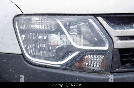 Scheinwerfer vorne rechts für Renault Duster. Crossover oder SUV in Weiß mit schwarzem Stoßfänger. Blick auf die Vorderseite des Fahrzeugs. Detaillierte Nahaufhellung auf einer Ca Stockfoto