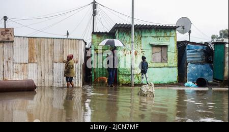 Kapstadt, Südafrika. 14.. Juni 2022. Am 14. Juni 2022 werden Menschen in einem überfluteten informellen Siedlungsgebiet in Kapstadt, Südafrika, gesehen. Eine Kaltfront verursachte am Montag und Dienstag starke Regenfälle in Kapstadt. Kredit: Xabiso Mkhabela/Xinhua/Alamy Live Nachrichten Stockfoto