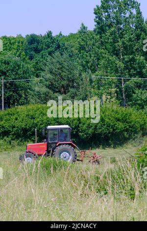 Bauer mit einer roten Traktor im grünen Feld in einem ländlichen Gebiet von Landschaft Zala in Ungarn arbeiten Stockfoto