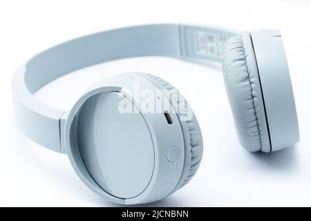 Nahaufnahme von grauen kabellosen Kopfhörern, isoliert auf weißem Hintergrund. Stockfoto