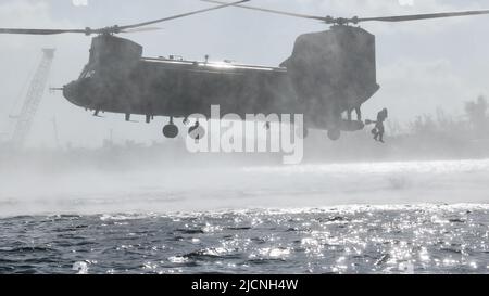 Ein Green Beret, der dem 2. Bataillon, der 10. Special Forces Group (Airborne), zugewiesen wurde, wirft von einem CH-47 Chinook Hubschrauber in der Nähe von Key West, Florida, 3. Mai 2022 in den Golf von Mexiko. Helocast, oder Free-Drop aus einem Hubschrauber, ist ein Mittel, um Kampfschwimmer/Taucher und maritime Mobilität Boote in eine wasserbasierte Umgebung einfügen. (USA Foto der Armee von Staff Sgt. Anthony Bryant) Stockfoto