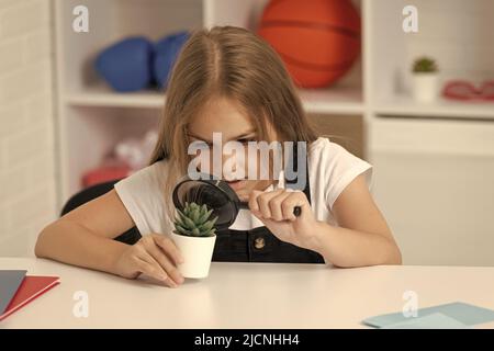 Wissenschaft und Kindheit. Jugendliches Mädchen, das die Pflanze durch Lupe betrachtet. Zurück zur Schule. Stockfoto